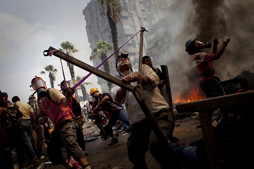 Premio Nacional de Fotoperiodismo 2014. Dos hombres utilizan un gran tirachinas durante los enfrentamientos en Raba Al Adaweeya (El Cairo). Foto: Andrés Martínez Casares